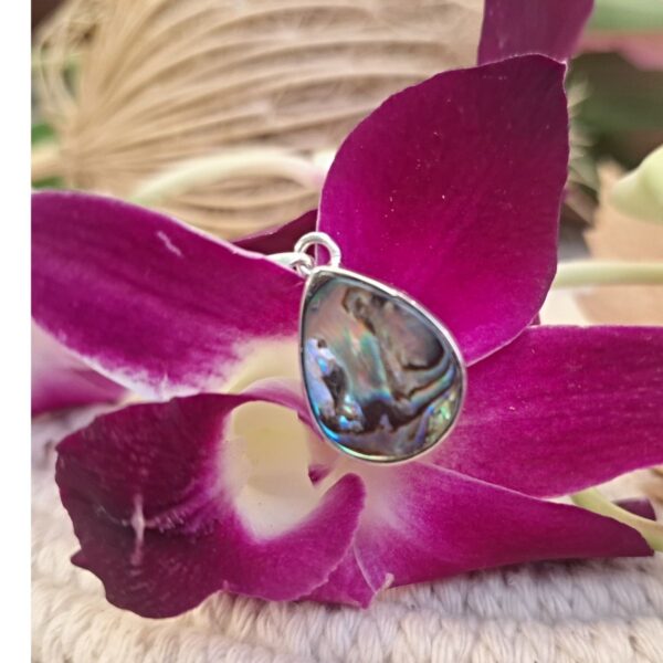 Silver abalone teardrop pendant with blue and violet shimmer on orchid flower